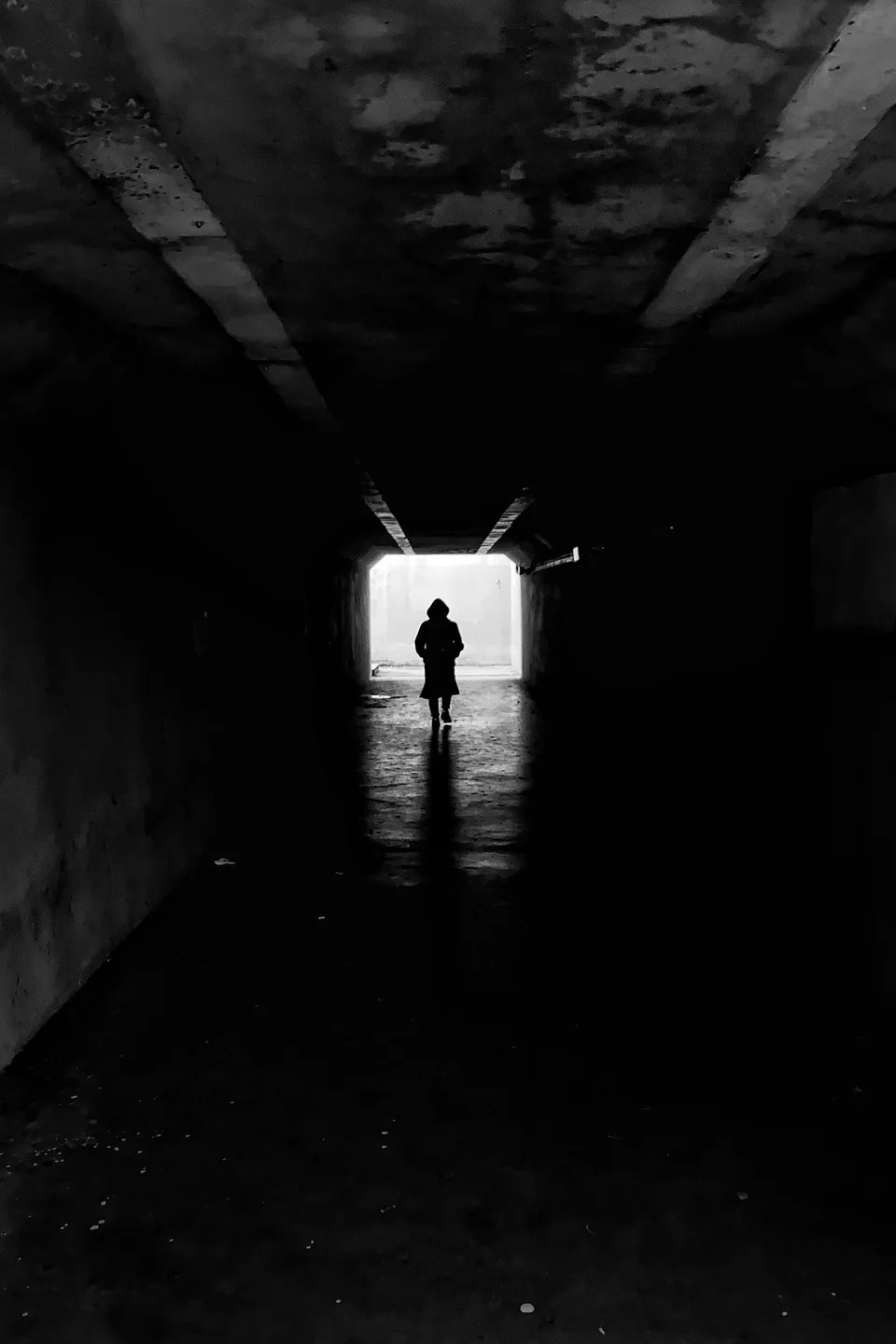 Silhouette marchant dans un couloir sombre vers la lumière, évocation d'une peur dépassée