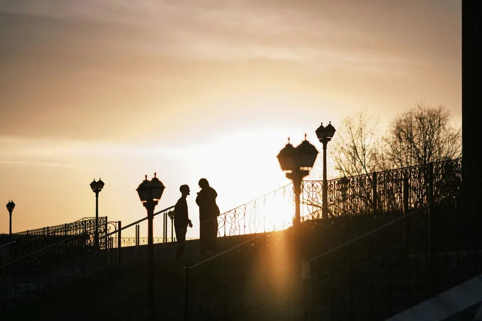 Deux silhouettes en conversation au coucher du soleil, évocation de la communication